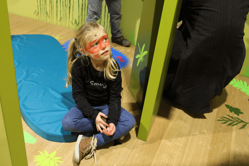 Enfant maquillée assise sur le sol de Crapahut : la drôle de forêt
