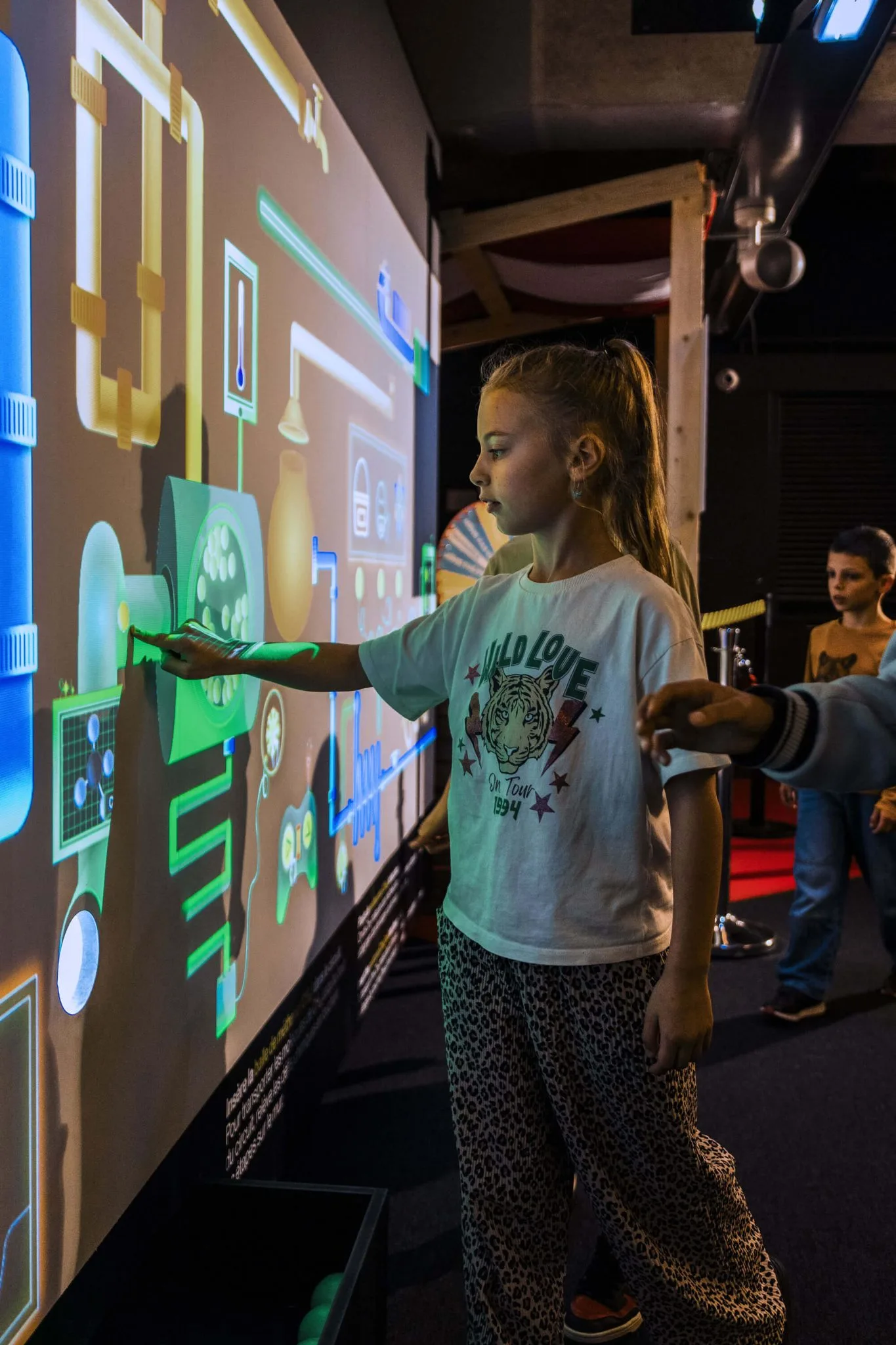 Petite fille touche le tableau interactif Le mur des éléments du SPARKOH!
