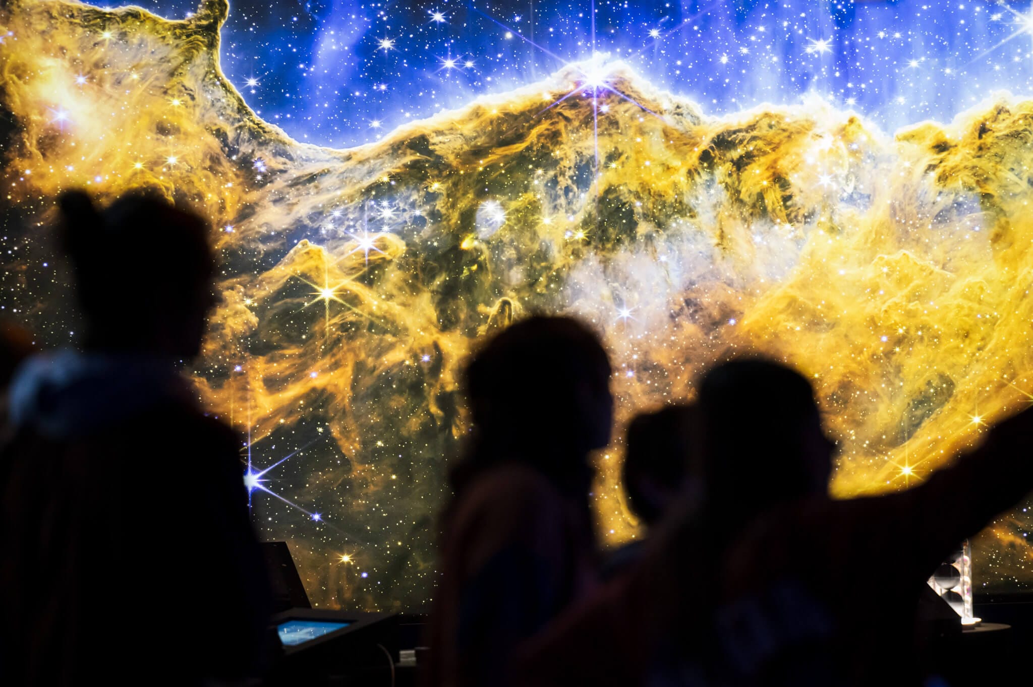 Exposition COSMOS au SPARKOH! silhouettes devant une photo des falaises cosmiques